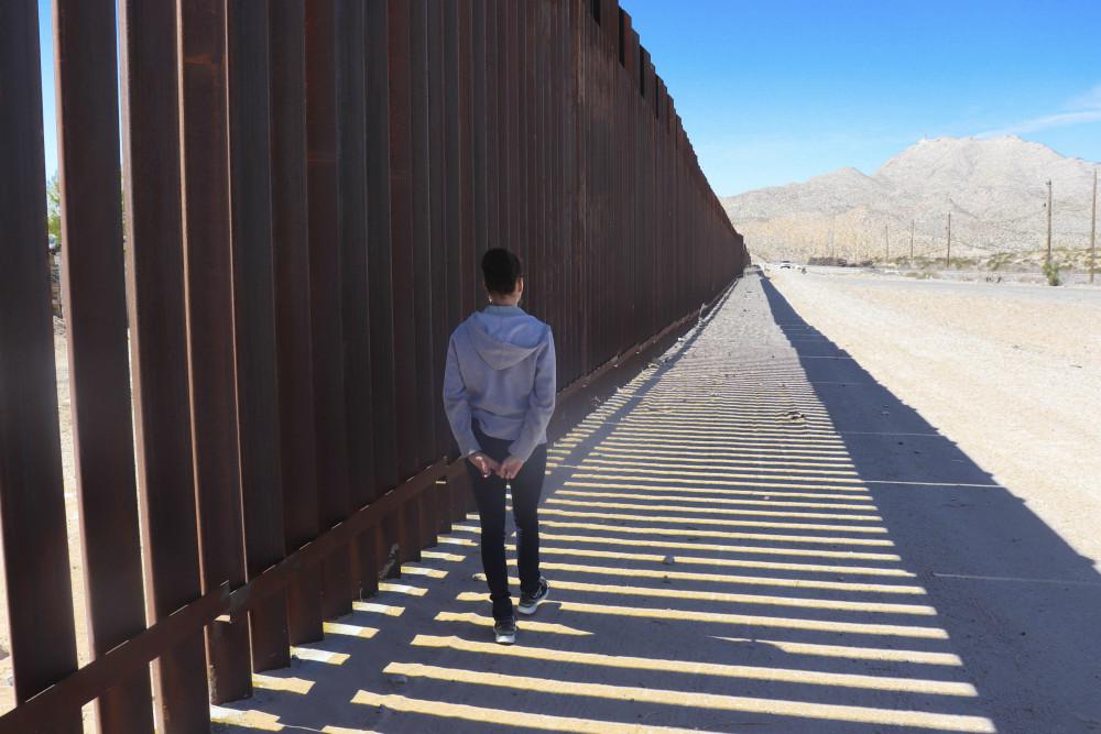 A Beloit College student walks a segment of the border wall between the United States and Mexico.
